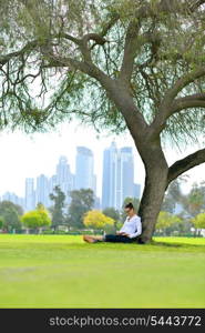 happy young student woman with laptop in city park study