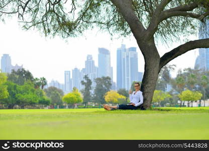 happy young student woman with laptop in city park study