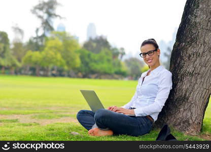 happy young student woman with laptop in city park study