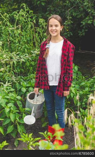 Happy young teen girl posing with watering can at garden