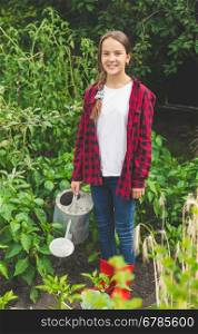 Happy young teen girl posing with watering can at garden