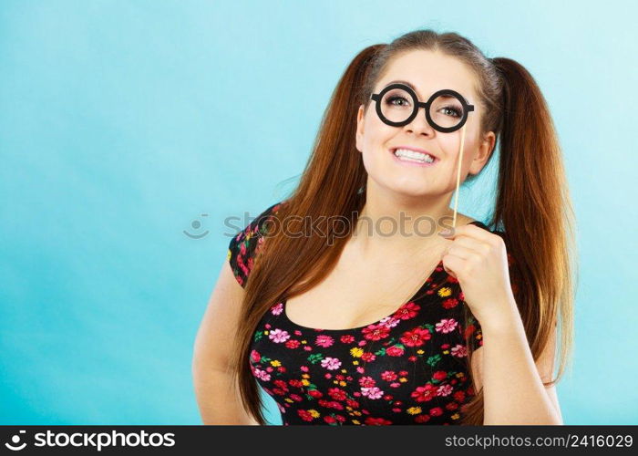 Happy young teenage woman holding fake eyeglasses on stick having fun. Photo and carnival funny accessories concept.. Happy teenage woman holding fake eyeglasses on stick