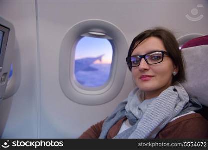 happy young tourist woman is sitting in the airplane looking windov and travel to summer vacation