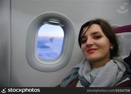 happy young tourist woman is sitting in the airplane looking window and travel to summer vacation