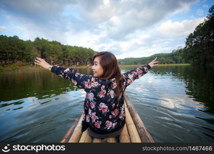 Happy young traveler woman raised arm up and lake view