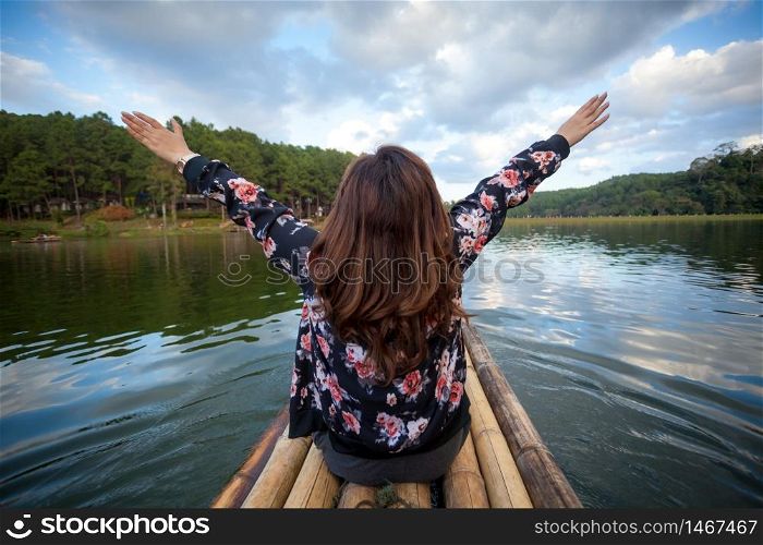 Happy young traveler woman raised arm up and lake view