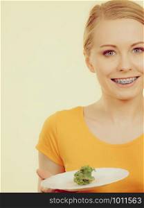 Happy young woman about to eat lettuce holding plate and smiling. Toned image colors.. Smiling woman holding plate with lettuce
