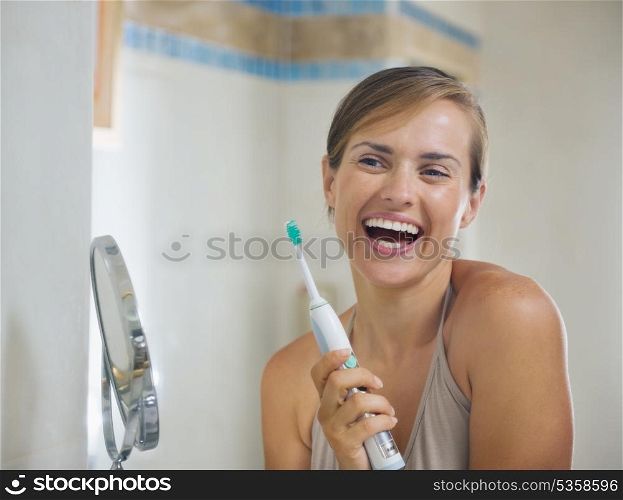 Happy young woman after brushing teeth with electric toothbrush