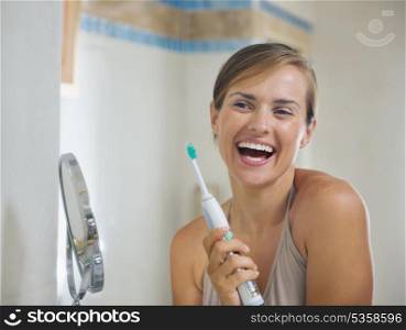 Happy young woman after brushing teeth with electric toothbrush