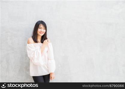Happy young woman against concrete wall.