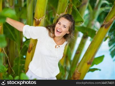 Happy young woman among tropical palms