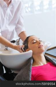 happy young woman at hair salon. beauty and people concept - happy young woman with hairdresser washing head at hair salon