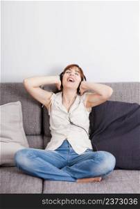 Happy young woman at home listening music with headphones