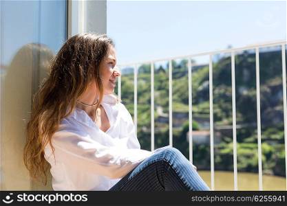 Happy young woman catching some sun at the balcony