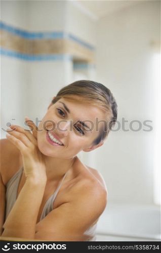 Happy young woman checking facial skin