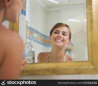 Happy young woman checking teeth after brush