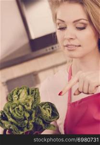 Happy young woman, cooking chef showing holding green lettuce. Female loving vegetables about to cook.. Womna holding green lettuce