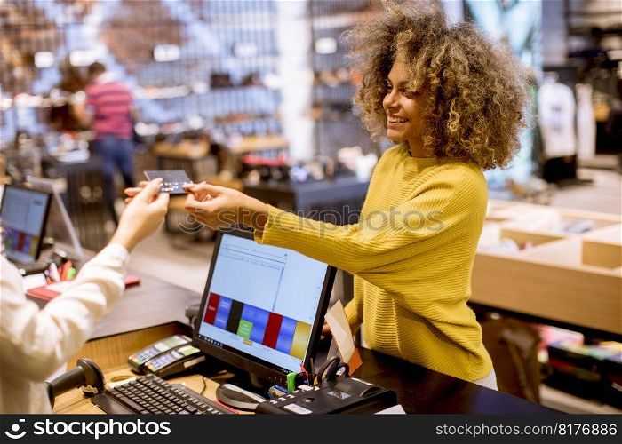 Happy young woman customer paying with credit card in fashion showroom