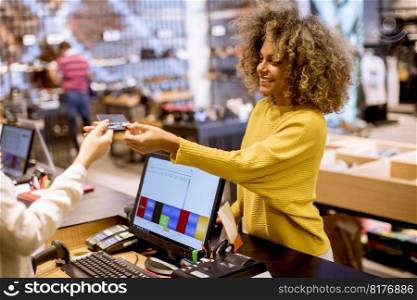 Happy young woman customer paying with credit card in fashion showroom