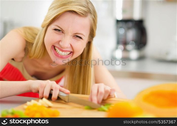 Happy young woman cutting fruits in kitchen