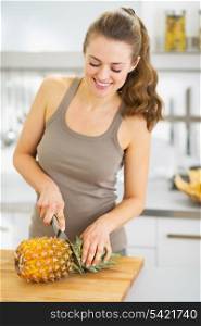 Happy young woman cutting pineapple