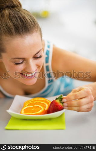 Happy young woman decorating plate with fruits