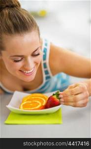 Happy young woman decorating plate with fruits