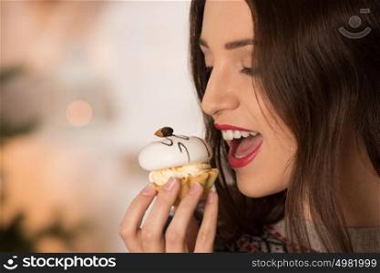 Happy young woman eating candy near christmas tree
