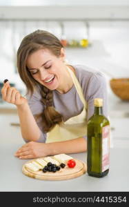 Happy young woman eating fresh cheese and olives