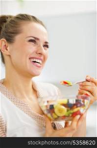 Happy young woman eating fresh fruits salad
