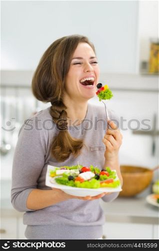 Happy young woman eating fresh salad