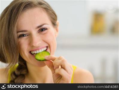 Happy young woman eating slice of cucumber