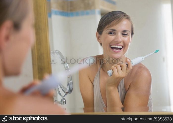 Happy young woman enjoying clean teeth after brushing electric teeth brush