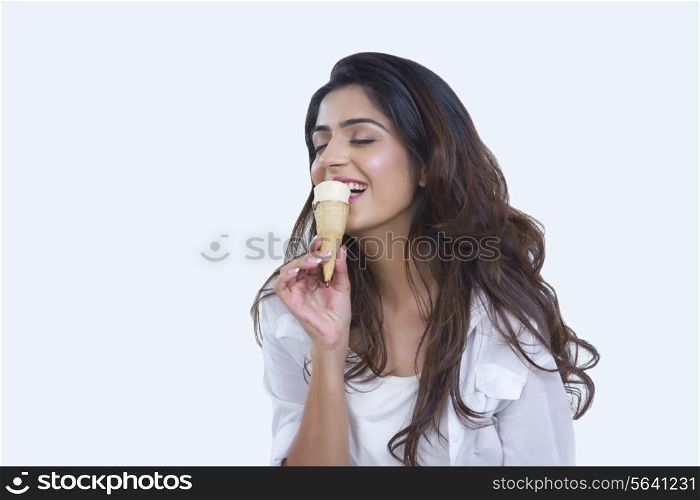 Happy young woman enjoying ice-cream cone over white background