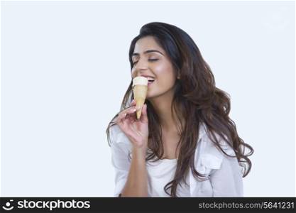 Happy young woman enjoying ice-cream cone over white background