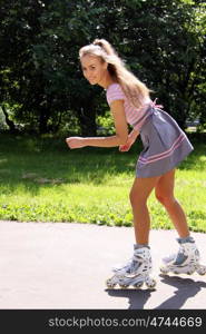 Happy young woman enjoying roller skating rollerblading on inline skates sport in park. Woman in outdoor activities