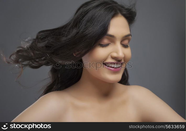 Happy young woman enjoying the breeze over colored background