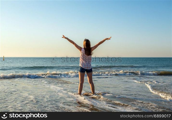 Happy young woman enjoys summer and sea in the evening light.Vacation,travel and freedom concept