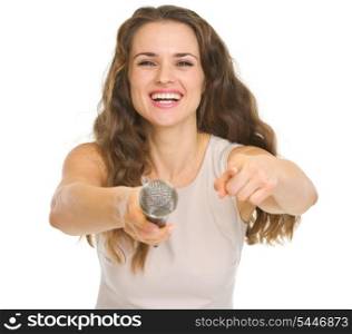 Happy young woman giving microphone and pointing in camera