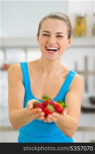 Happy young woman giving strawberries