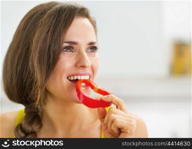 Happy young woman having a bite of red bell pepper