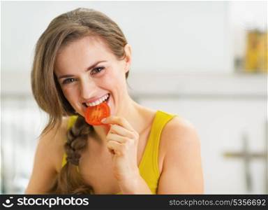 Happy young woman having a bite of red tomato