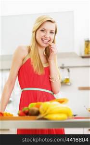 Happy young woman having a bite while cutting salad