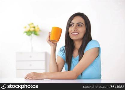 Happy young woman having coffee at home