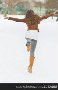 Happy young woman having fun in winter park . rear view