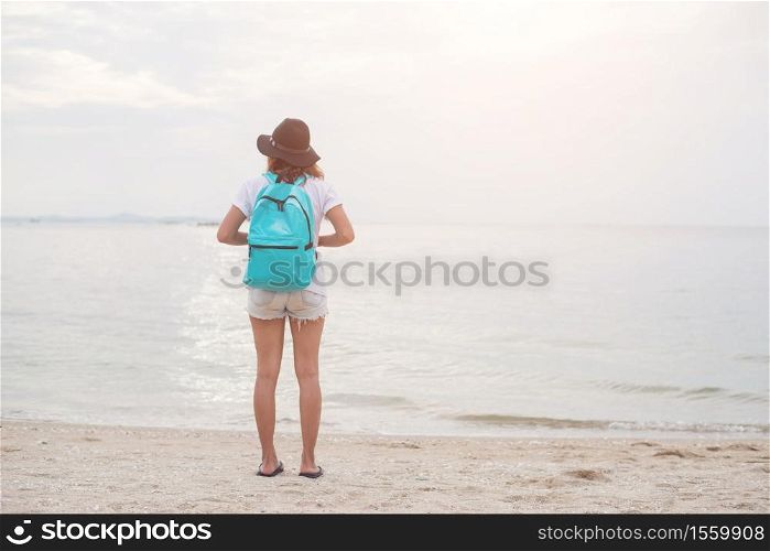 Happy young woman having fun on her vacation,holding backpack,Standing on the beach. Freedom enjoy women on the beach.