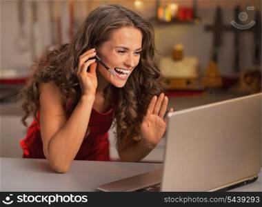 Happy young woman having video chat on laptop in christmas decorated kitchen