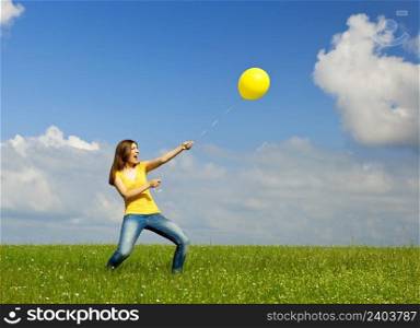 Happy young woman holding a yellow balloon with strenght
