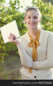Happy young woman holding an ipad outdoors