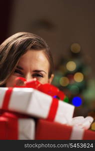 Happy young woman holding christmas present boxes in front of face